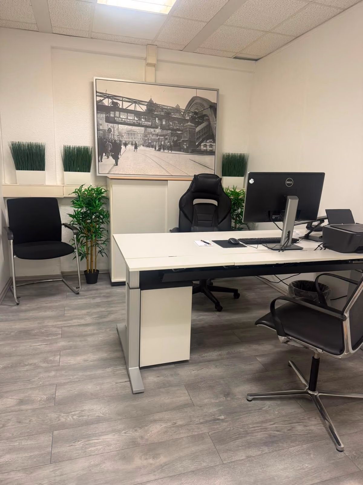 Einzelbüro mit großem Schreibtisch, Monitor und Besucherplätzen